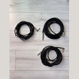 Tři černé audio kabely s kovovými konektory typu jack. Kabely jsou svinuté do klubíčků a položené na světlém laminátovém povrchu. Na konektorech nejs…