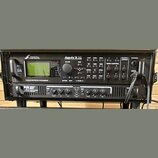 Černý rack s dvěma zařízeními. Horní jednotka má nápisy FRACTAL AUDIO SYSTEMS a Axe-Fx II XL, dále označení PREAMP/EFFECTS PROCESSOR, displej a řadu…