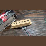 Kremově bílý humbucker s šesti viditelnými póly, vedoucími z něj čtyři barevné vodiče (červený, bílý, zelený a černý). Vedle nástroje je umístěna kra…