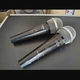 Dvě dynamické mikrofony s černým tělem a stříbrnými mřížkami. Na horním mikrofonu je nápis SHURE C606 a přepínač s označením ON a OFF. Dolní mikrofon…