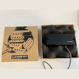 Kartonová krabice s černým potiskem a nápisy „Lunogren guitar pickups“ a „HANDMADE GUITAR PICKUPS · SWEDEN“. Vedle krabice je otevřené balení s černý…