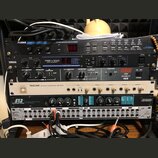 Sestupka rackových zařízení v černém a stříbrném provedení. Z horní části dolů jsou viditelné nápisy: ALESIS MIDIVERB III, YAMAHA REV100 DIGITAL REVE…