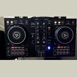 Černý DJ controller s dvěma jogovými koly a centrálním míchacím panelem. Na horní části je nápis PERFORMANCE CONTROLLER DDJ-400 a logo rekordbox, v d…