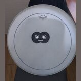 Bílá bubnová blána s modrým vnějším kruhem. V horní části je logo REMO pod symbolem koruny, ve středu se nachází černý ovál s dvěma bílými symboly a…