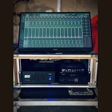 Na fotce je vidět monitor značky Iiyama, na kterém je zobrazeno rozhraní pro ovládání zvukového mixu s názvem Rack 1. Monitor je umístěn na hliníkové…