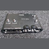 Černý zvukový interface Line 6 UX2. Na horní straně jsou čtyři chromované otočné ovladače s nápisy MIC 1/L GAIN, MIC 2/R GAIN, OUTPUT a PHONES. V pře…
