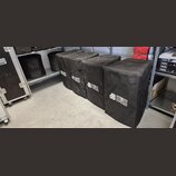 Pět černých transportních krytů z látky, které jsou umístěny v řadě na podlaze a polici. Na každém krytu je bílý nápis dB TECHNOLOGIES. Povrch látky…