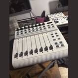Bílý USB MIDI kontrolér s osmi posuvníky a řadou otočných knoflíků v horní části. Na pravé straně jsou umístěna tlačítka a nápisy B-CONTROL, MIDI FAD…