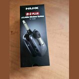 Černá krabice s produktem NUX B-2 PLUS 2.4GHz Wireless System for Guitar. Na balení je zobrazen obrázek bezdrátového systému pro kytaru v černé barvě…