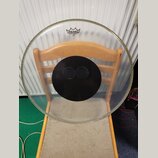 Průhledná bubenová blána s černým kruhem uprostřed a dvěma malými otvory. V horní části je černé logo REMO s nápisem CONTROLLED SOUND a pod ním nečit…