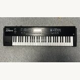 Černý digitální klavír s bílými a černými klávesami. Na levé straně je bílý nápis Roland JUNO-D. Horní panel obsahuje displej, několik tlačítek a oto…