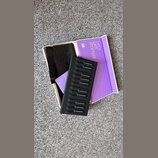Fotografie zobrazuje otevřenou fialovou krabici s nápisem Let's get started a QR kódem. Uvnitř je černý plastový držák s osmi sloty pro příslušenství…