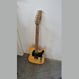 Elektrická kytara s přírodním žlutým povrchem těla a hnědým hmatníkem. Na hlavě je viditelné logo "Brand". Kytara má černý pickguard a kovový most sá…