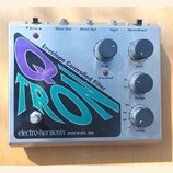 Kytarový efekt v kovovém šasi s nápisem Q TRON a textem Envelope Controlled Filter. Na přední straně jsou čtyři ovládací knoflíky s popisky Peak, Gai…