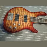 Elektrická basová kytara s tělem z plamenového javoru v červeně-žlutém gradientním lakování. Nástroj má dva černé humbuckery, čtyři chromované ovláda…