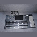 Černý pedalboard s nápisem HEAD RUSH PEDALBOARD a logem ELEVEN HD EXPANDED. Zařízení obsahuje displej, několik ovládacích knoflíků a řadu stomačů. Na…