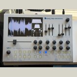 Stříbrný granulární syntetizátor s nápisem GR-1 Granular Synthesizer a logem tasty chips electronics. Zařízení má displej s vizualizací vlnovky, něko…