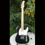 Elektrická kytara s černým trupem, bílým pickguardem a světlou hnedou hmatníkem. Na hlavě je viditelné logo "Fender". Kytara má jeden krkový snímač a…