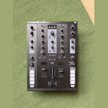Černý DJ kontroler s nápisem TRAKTOR KONTROL Z2 a logem NI v pravém horním rohu. Zařízení obsahuje dva kanály s knoflíky Gain, Mid a Low, faderem hla…