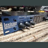 Modrý rackový efektový procesor s nápisem Lexicon MX200 Dual Reverb Effects Processor. Na předním panelu jsou tři černé otočné ovladače a sekce INPUT…