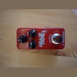 Červený kytarový efekt s nápisy HALL OF FAME 2 MINI a tc electronic. Na horní straně jsou tři černé otočné oválné knoflíky s popisky LEVEL, TONE a ne…