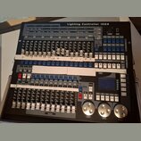 Černý světelný kontrolér s nápisem Lighting Controller 1024. Zařízení obsahuje množství posuvníků, tlačítek a tři velké stříbrné otočné ovladače v do…