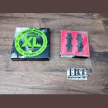 Fotografie zobrazuje tři předměty na hnědém dřevěném povrchu. Vlevo je černá krabička s nápisy NICKEL WOUND, D'Addario, XL a EXL165TP. Uprostřed je č…