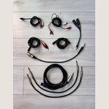 Sada různých audio kabelů v černé barvě rozložená na světlé podložce. Jsou zde kabely s konektory RCA (červené a bílé), jack 3,5 mm, 6,35 mm oraz XLR…