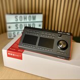 Šedý rackový audio rozhraní s nápisem REDNET R1 a logem Focusrite. Zařízení má dvě displejové obrazovky, řadu tlačítek a velký ovládací knoflík s náp…