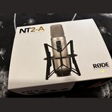 Bílá krabice s nápisem NT2-A MULTI-PATTERN STUDIO CONDENSER MICROPHONE a logem RØDE MICROPHONES. Na krabici je zobrazen stříbrný kondenzátorový mikro…