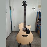 Akustická kytara s vyřezem v těle, světlým povrchem desky a tmavým hmatníkem. Na hlavě je bílé logo "IF". U otvoru zvukové díry je vidět štítek s náp…