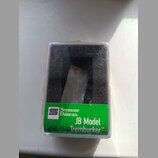 Průhledný plastový obal s černou vložkou, ve kterém je umístěn kytarový snímač. Na spodní straně obalu je zelená nálepka s logem a nápisem Seymour Du…