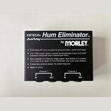 Černý box s nápisem EBTECH® Hum Eliminator™ by MORLEY®. Na povrchu je text popisující funkce zařízení a poznámka Made in U.S.A. V dolní části jsou dv…