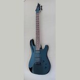 Elektrická kytara s tmavě modrým lakovaným tělem a hnědým hmatníkem. Na hlavě je bílé logo Cort. Nástroj má dva humbuckery, fixační most a dvě ovláda…