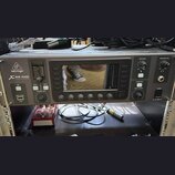 Šedý rackový digitální mixér s nápisem behringer X32 RACK POWERED BY MIDAS. Zařízení má centrální displej, několik ovládacích tlačítek a pět otočných…