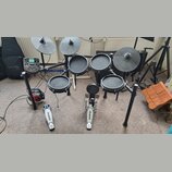 Elektronická bicí souprava s černými pady a činely. Na modulu, činelech a pedálech je viditelné logo ALESIS; na modulu je dále nápis NITRO. Souprava…