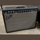 Kytarový zesilovač s černým povrchem a šedou síťovkou. Na přední straně je bílé logo Fender a v pravém dolním rohu nápis Tone Master. V horní části s…