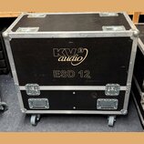 Černý transportní case s hliníkovými hranami a rohovými chrániči, osazený čtyřmi kolečky. Na přední straně je zlatým nápisem logo KV audio 2 a pod ní…