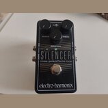 Černý kytarový efekt s nápisy THE SILENCER a noise gate/effects loop. Na horní straně jsou tři černé ovládací knoflíky s popisky RELEASE, REDUCTION a…