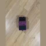 Fialový kytarový efekt Boss Flanger BF-3. Na horní straně jsou ovládací knoflíky s nápisy RES, MANUAL, DEPTH a RATE spolu s přepínači MODE (Standard/…