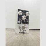 Bílý kytarový efekt s černým grafickým potiskem krajiny. Na horní straně jsou tři bílé otočné knoflíky s popisky Tone, Volume a Gain, dva přepínače o…