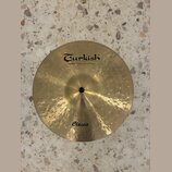Kruhové činely z mosazného kovu s kovaným povrchem. Na horní části je černý nápis Turkish a pod ním menší text handmade cymbals from Turkey. Ve spodn…