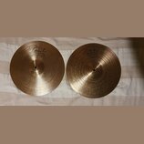 Dvě zlatavé kovové činely s koncentrickým rýhováním. Na obou je viditelné logo Paiste a nápis INNOVATION. Povrch je čistý bez viditelných poškzení.