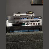 Sada rackového audio vybavení v černém case. Z horní části dolů jsou vidět zařízení s nápisy: Lexicon MPX 100 Dual Channel Processor, nečitelný příst…