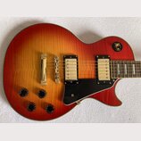 Elektrická kytara s tělem v červeno-žlutém sunburst provedení a černým pickguardem. Nástroj má dva humbuckery s krémovými kryty a čtyři černé ovládac…