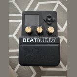 Černý efekt pedál s nápisem BEATBUDDY a pod ním vylisovaným logem SINGULAR SOUND. Zařízení má malý displej, čtyři šipkové tlačítka s nápisem TAP a tř…