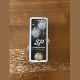 Kompresorový pedál s bílým rámem a černým horním panelem. Na panelu je bílý nápis „SP compressor BY xotic usa“. Pedál má dva průhledné ovládací knofl…