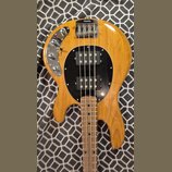 Kytara s přírodním dřevěným povrchem a černým kruhovým pickguardem. Na těle jsou dva černé humbuckery, chromovaný most a ovládací panel s dvěma knofl…