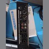 Zadní strana černého audio rozhraní s nápisy SSL 2+ a Solid State Logic. Jsou zde viditelné konektory USB, MIDI IN a OUT, dva výjemy PHONES, pět OUTP…