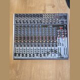 Stříbrný mixážní pult značky behringer s označením XENYX 2442USB. Zařízení obsahuje numerous vstupní konektory, posuvníky a ovládací knoflíky v modré…